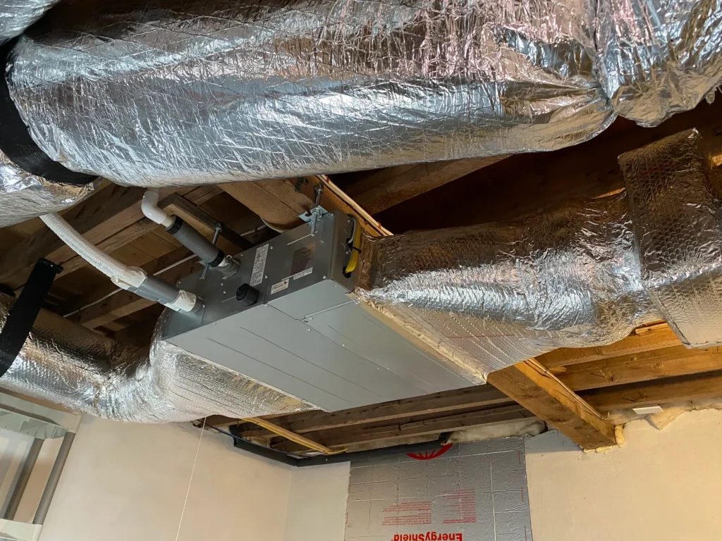 A room with duct work and insulation on the ceiling.