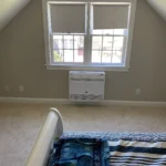 A bedroom with an air conditioner and window.