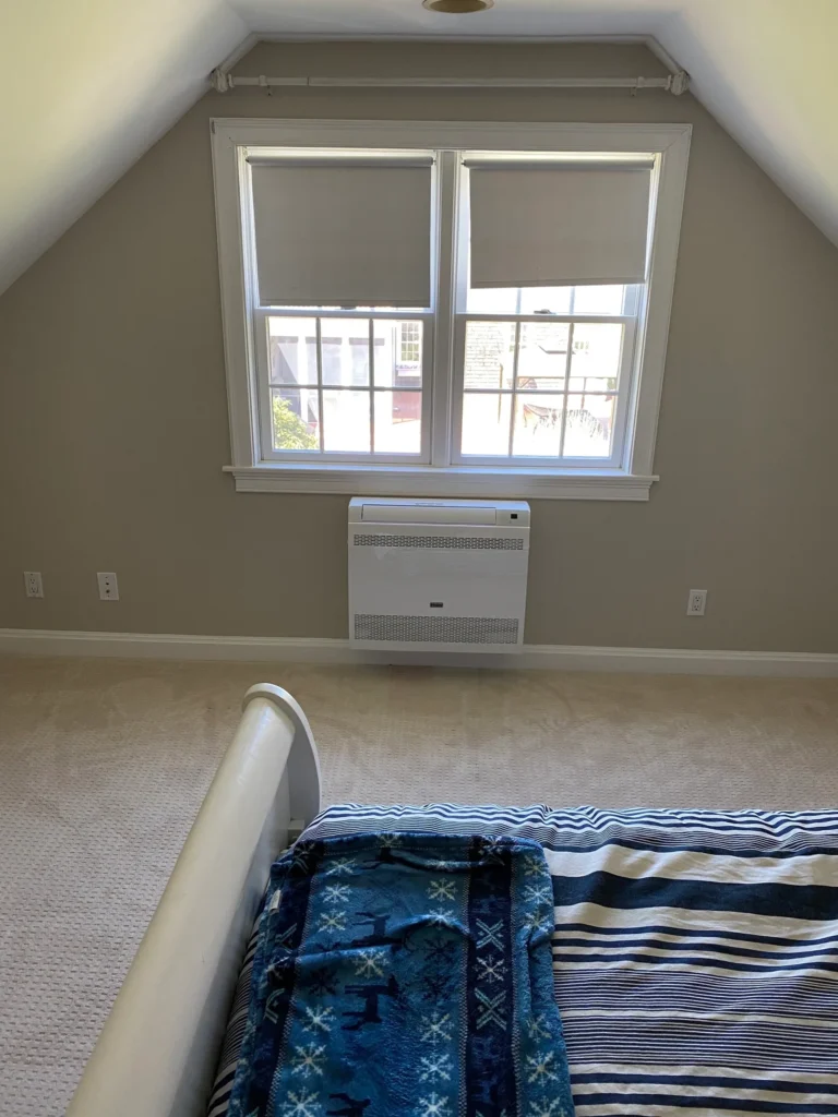 A bedroom with an air conditioner and window.