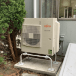 A small heat pump sitting outside of a house.