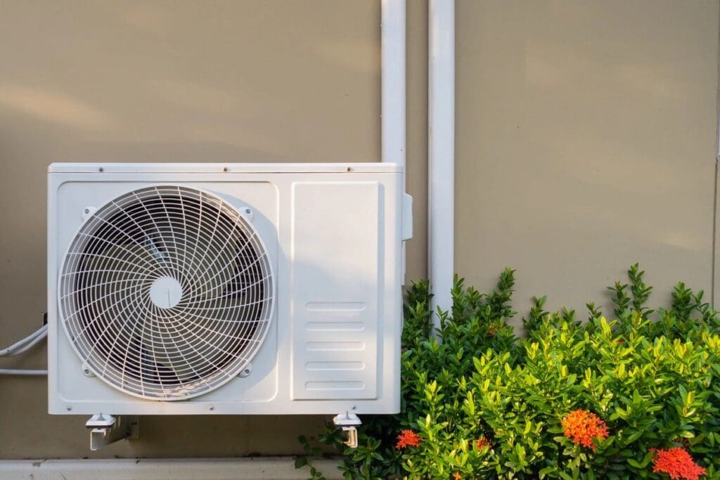 A white air conditioner sitting onside of a building.